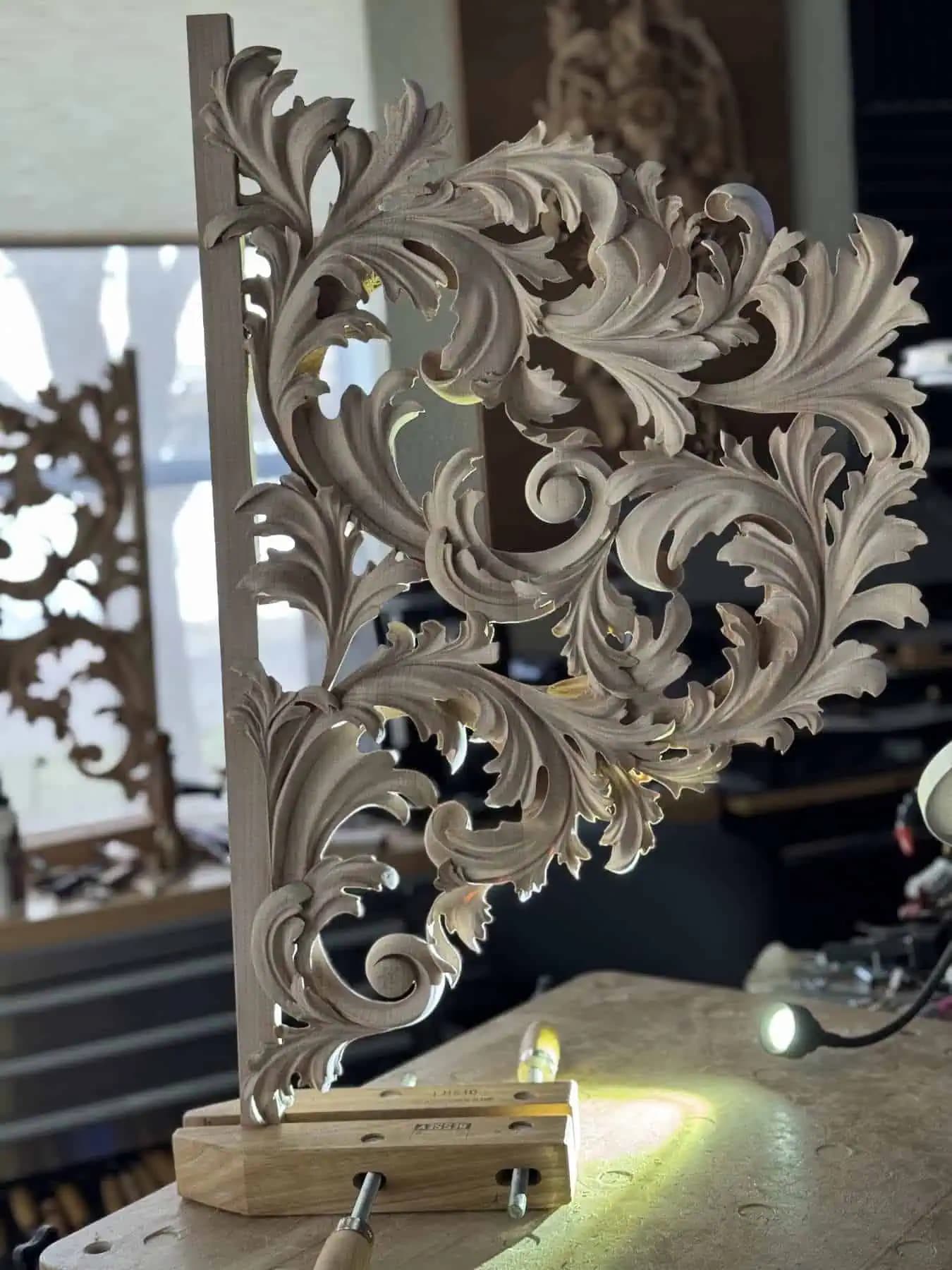 Pipe organ shade with flowing acanthus scrollwork, a custom wood carving by Alexander Grabovetskiy clamped at the bench.