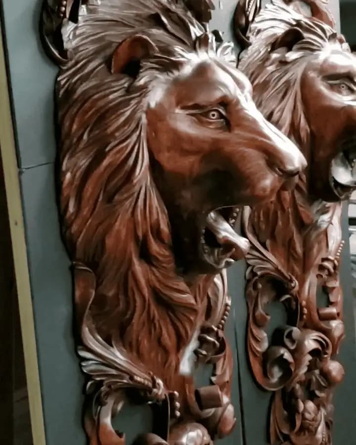 Lion heads with flowing manes in high-relief limewood, a custom wood carving by Alexander Grabovetskiy.