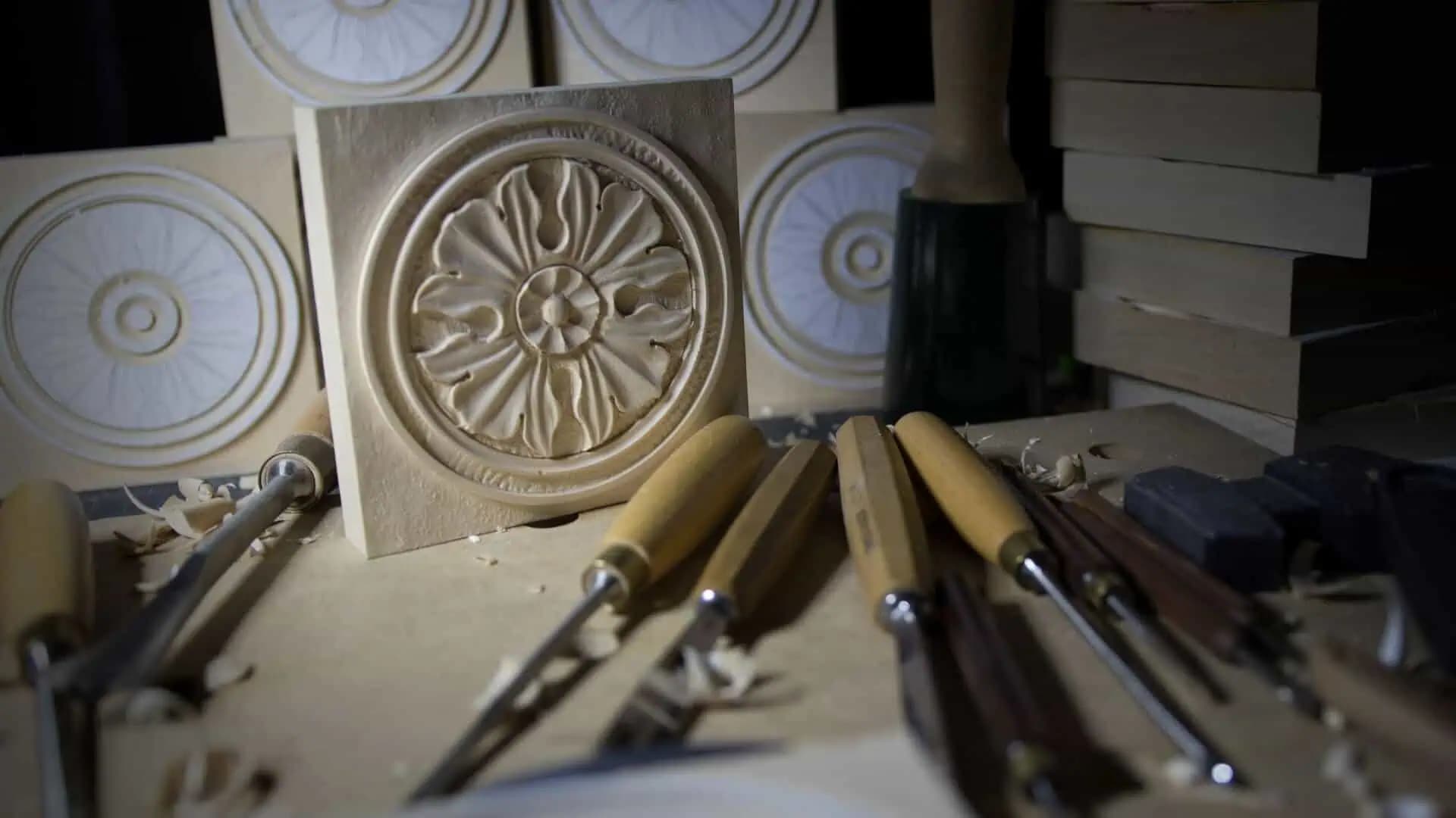 Square limewood rosette panel hand-carved by Alexander Grabovetskiy, a custom wood carving on a carving bench with chisels.