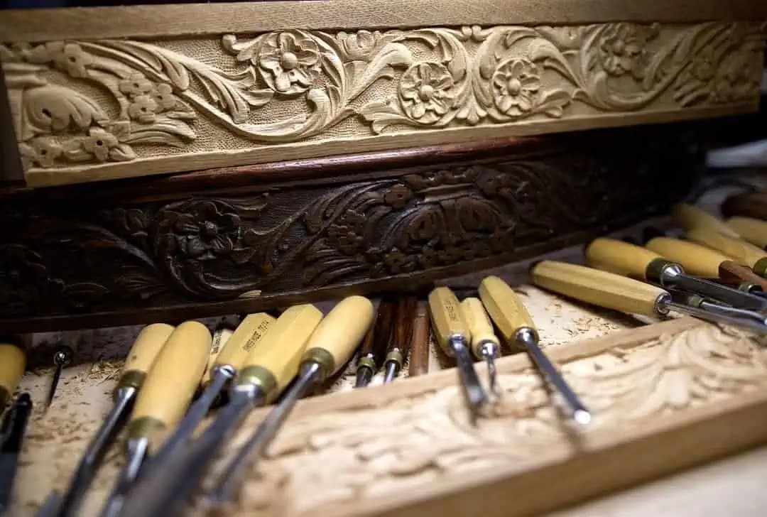 Floral scroll moldings beside carving gouges, custom wood carving by Alexander Grabovetskiy in his studio.