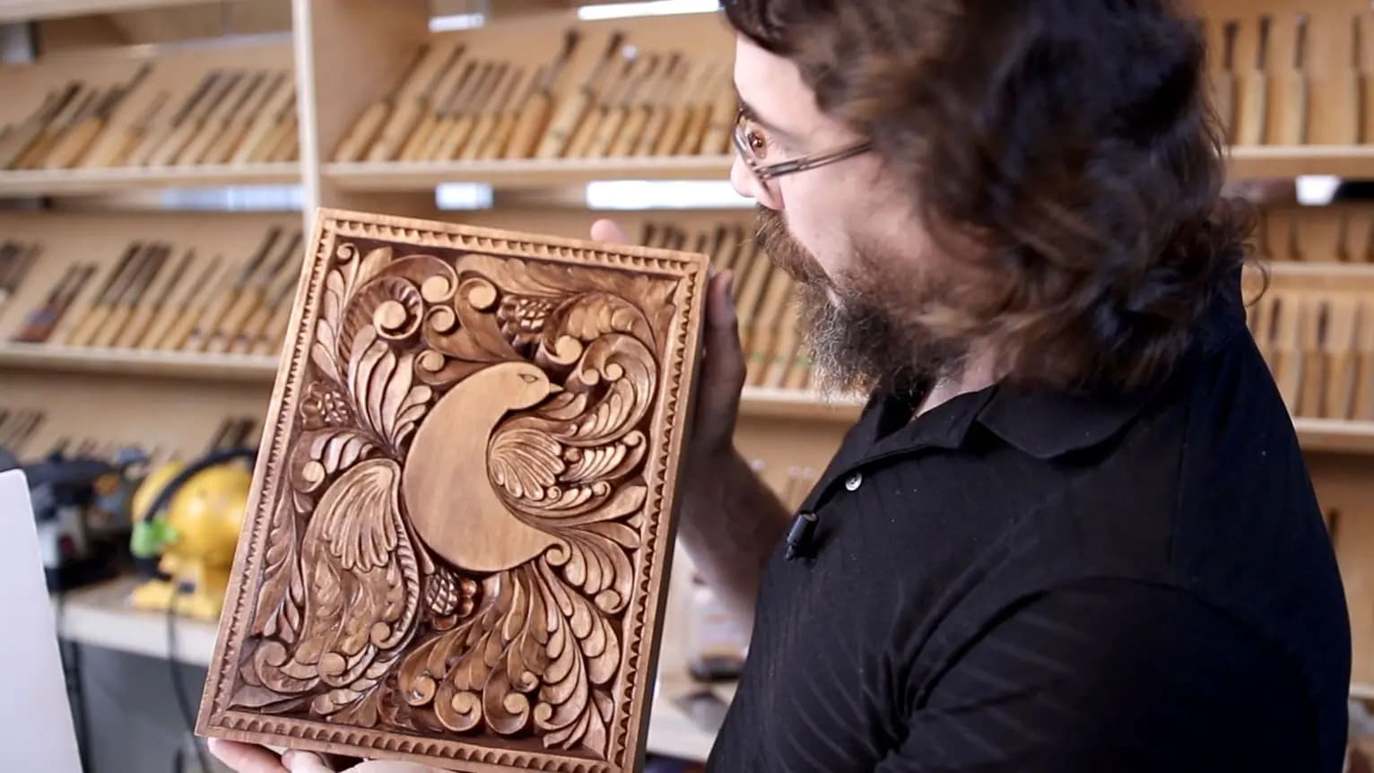 Alexander Grabovetskiy holds a limewood relief panel of a bird amid acanthus scrolls, a custom wood carving.