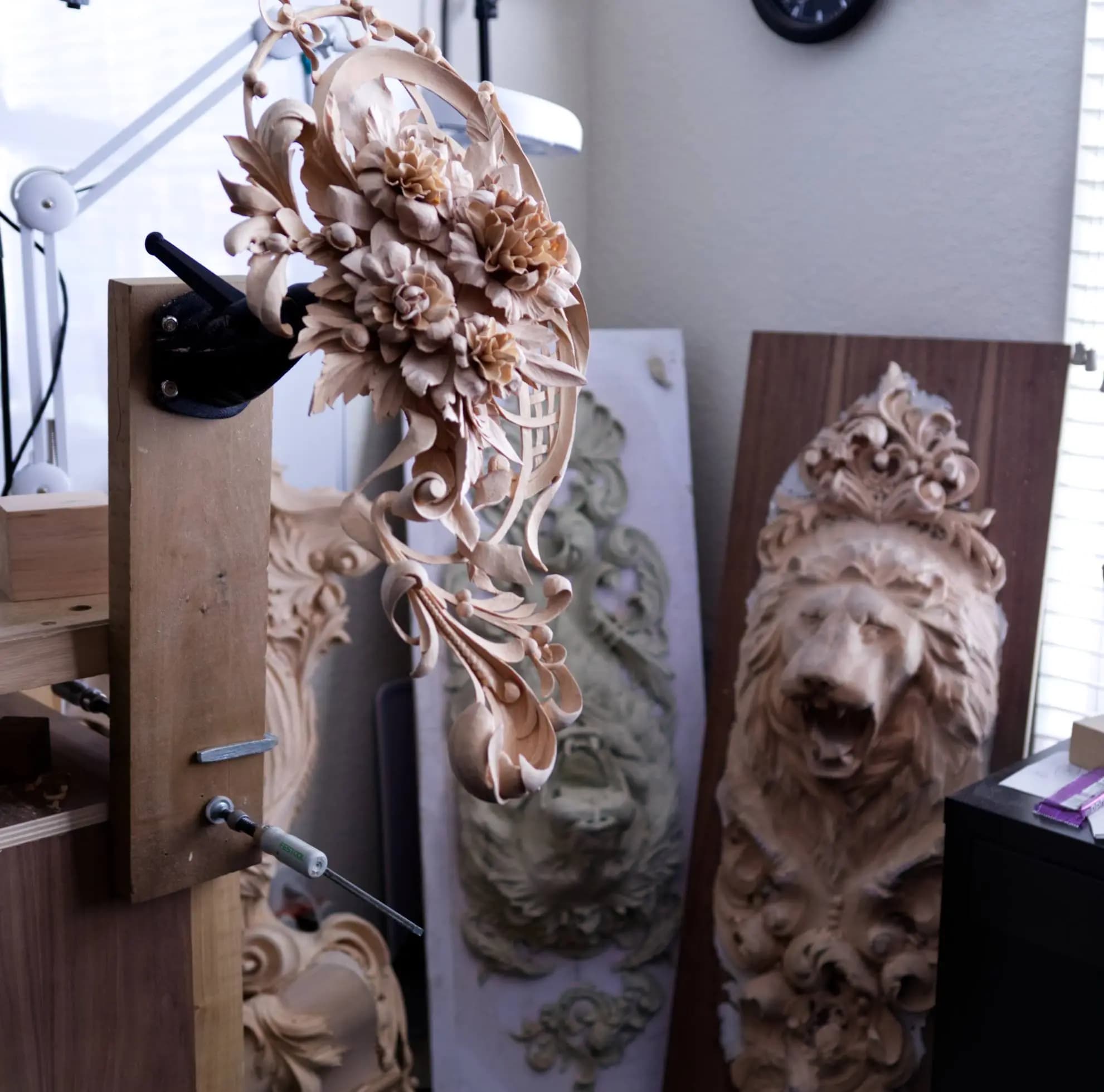 Limewood floral cartouche and lion relief, a custom wood carving by Alexander Grabovetskiy in his studio.