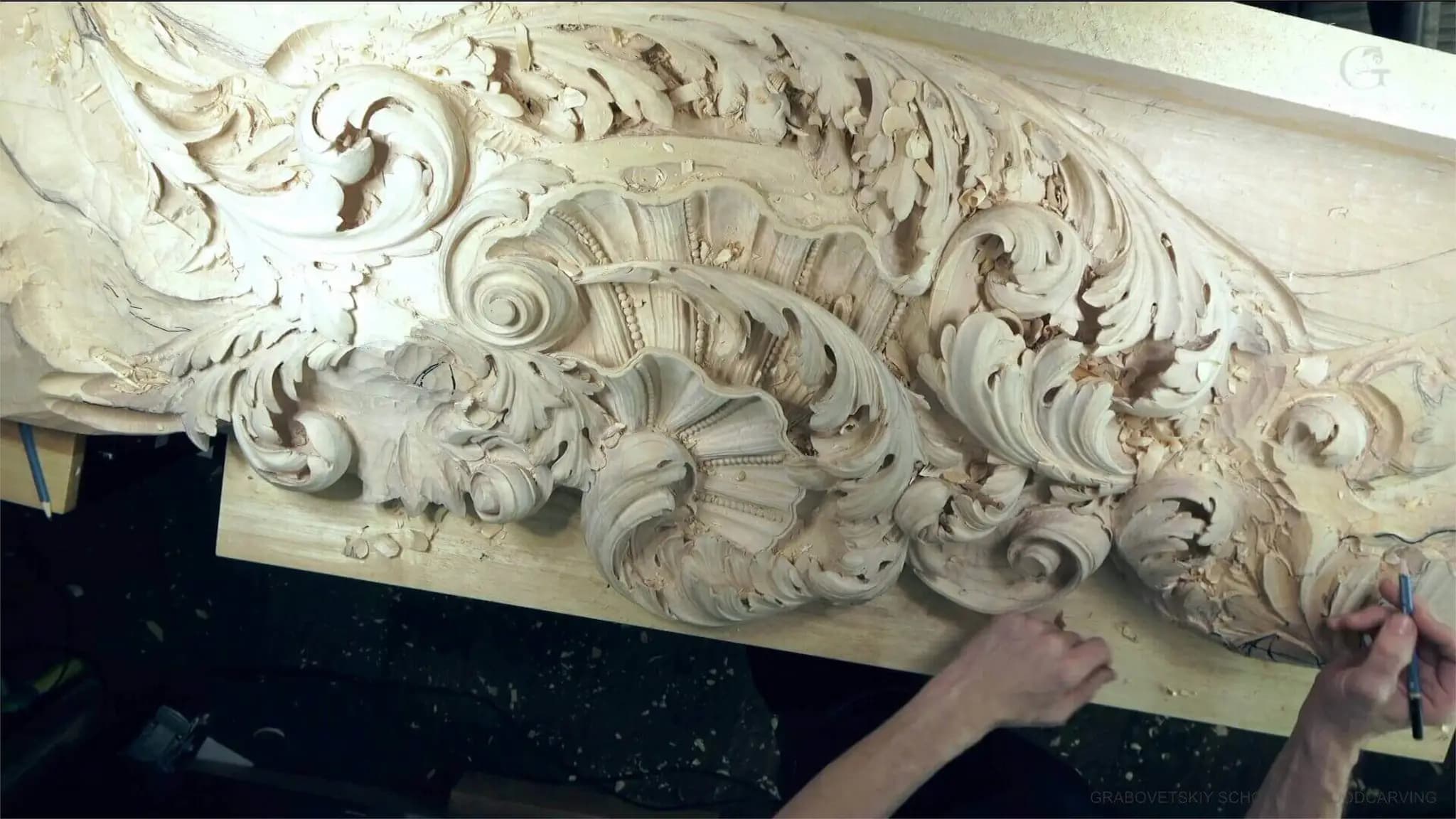 Alexander Grabovetskiy hand-shaping a Baroque shell and acanthus frieze as custom wood carving on his bench.