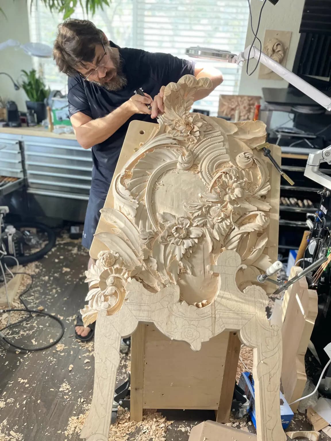 Alexander Grabovetskiy carving a Rococo floral cartouche headboard, a custom wood carving in progress.