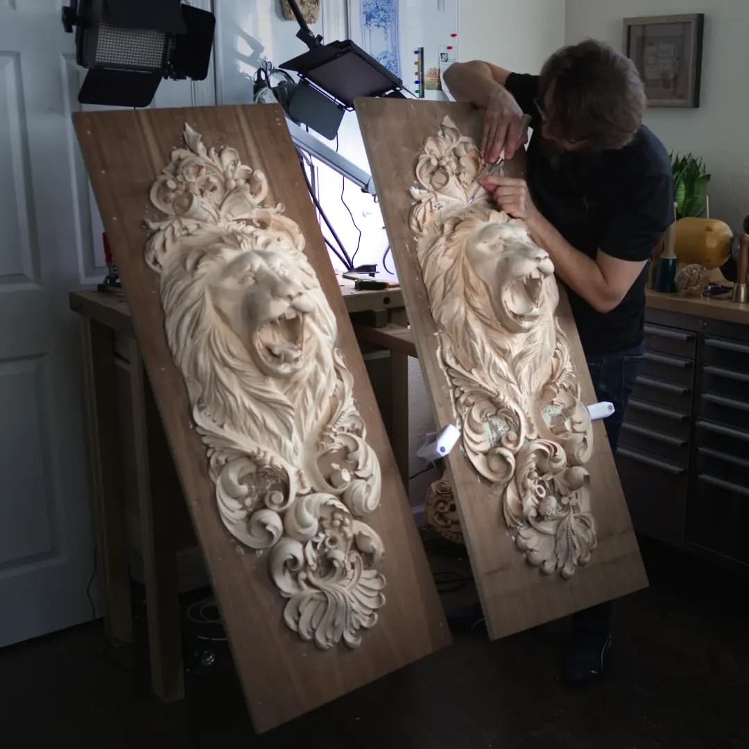 Alexander Grabovetskiy carving a roaring lion head limewood panel in his studio, a commission wood carving in progress.