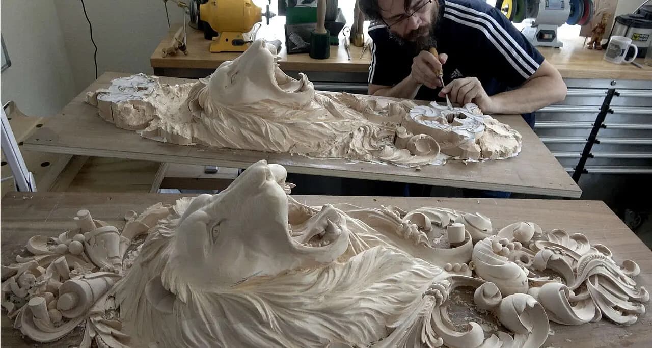 Alexander Grabovetskiy carving a pair of limewood lion heads in this custom wood carving in his studio.
