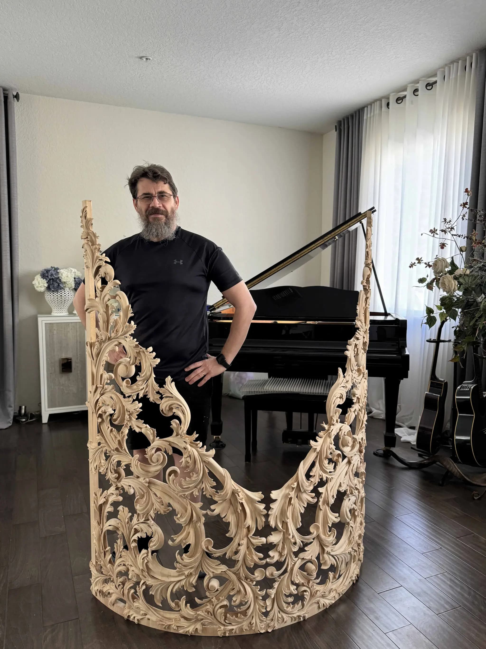 Alexander Grabovetskiy stands beside a curved limewood organ shade, a custom wood carving of pierced acanthus scrolls.