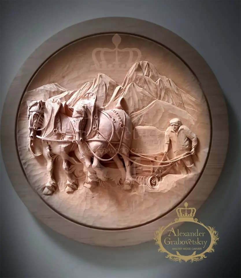 Round limewood relief of a farmer plowing with two draft horses below mountains, custom wood carving by Alexander Grabovetskiy.
