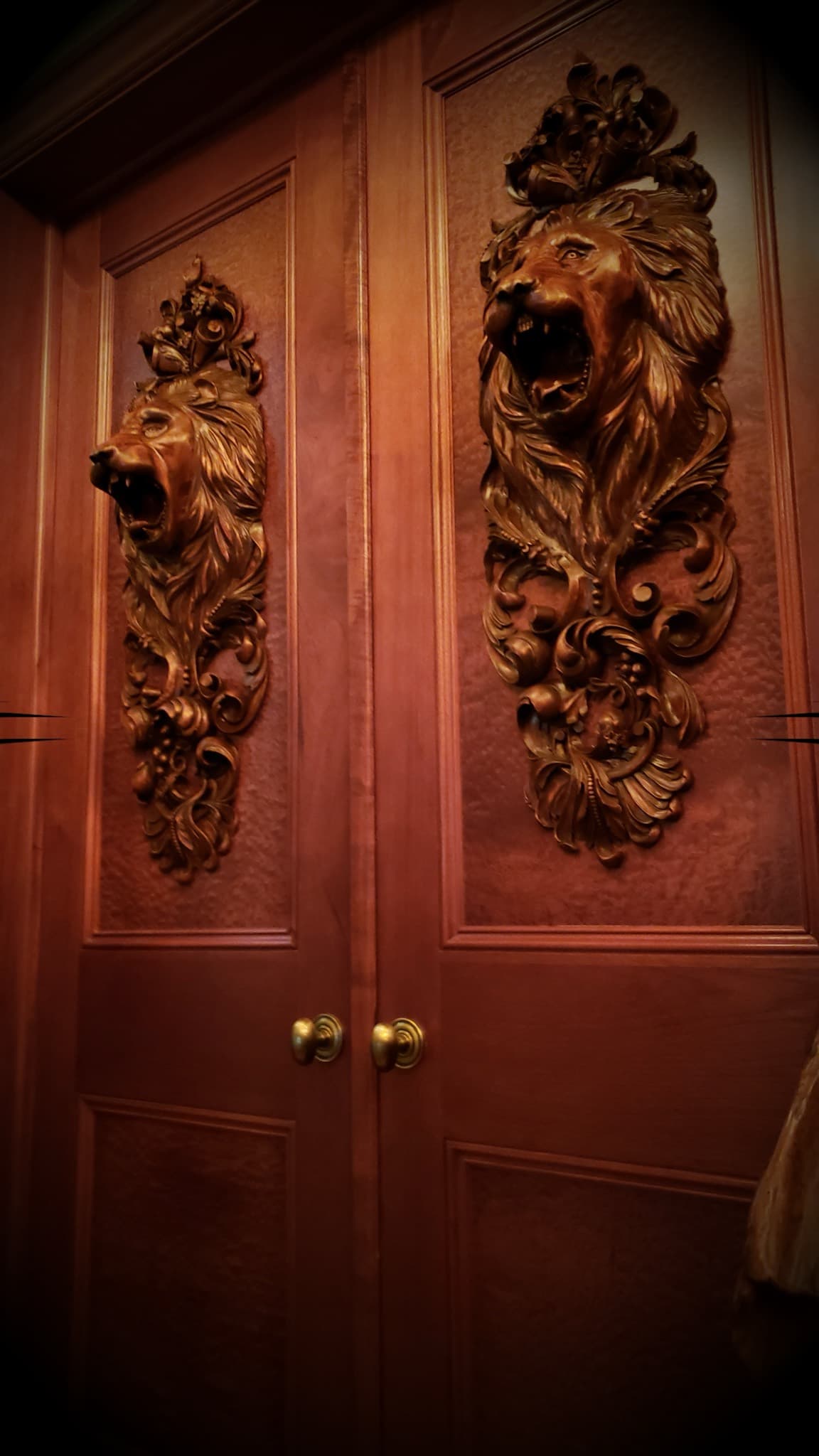 Two roaring lion head panels with acanthus scrollwork carved by Alexander Grabovetskiy as custom wood carving on double doors.