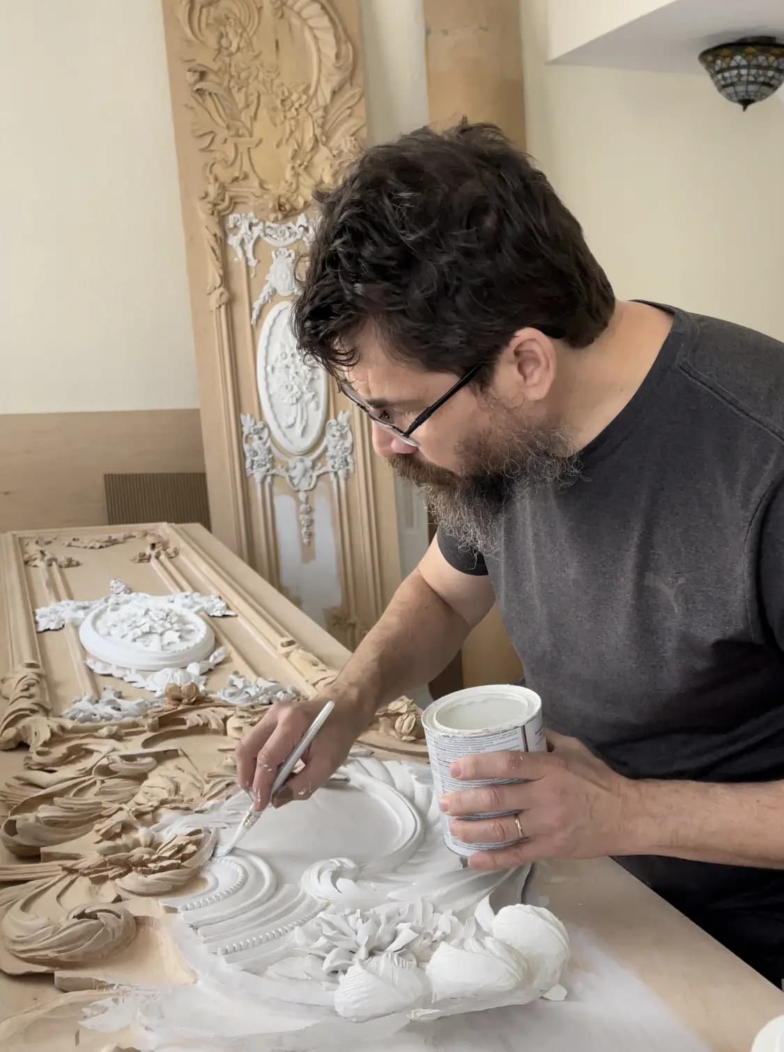 Rococo Scrollwork Panel in Progress Alexander Grabovetskiy applies primer to a carved Rococo scroll panel, a custom wood carving in his studio.